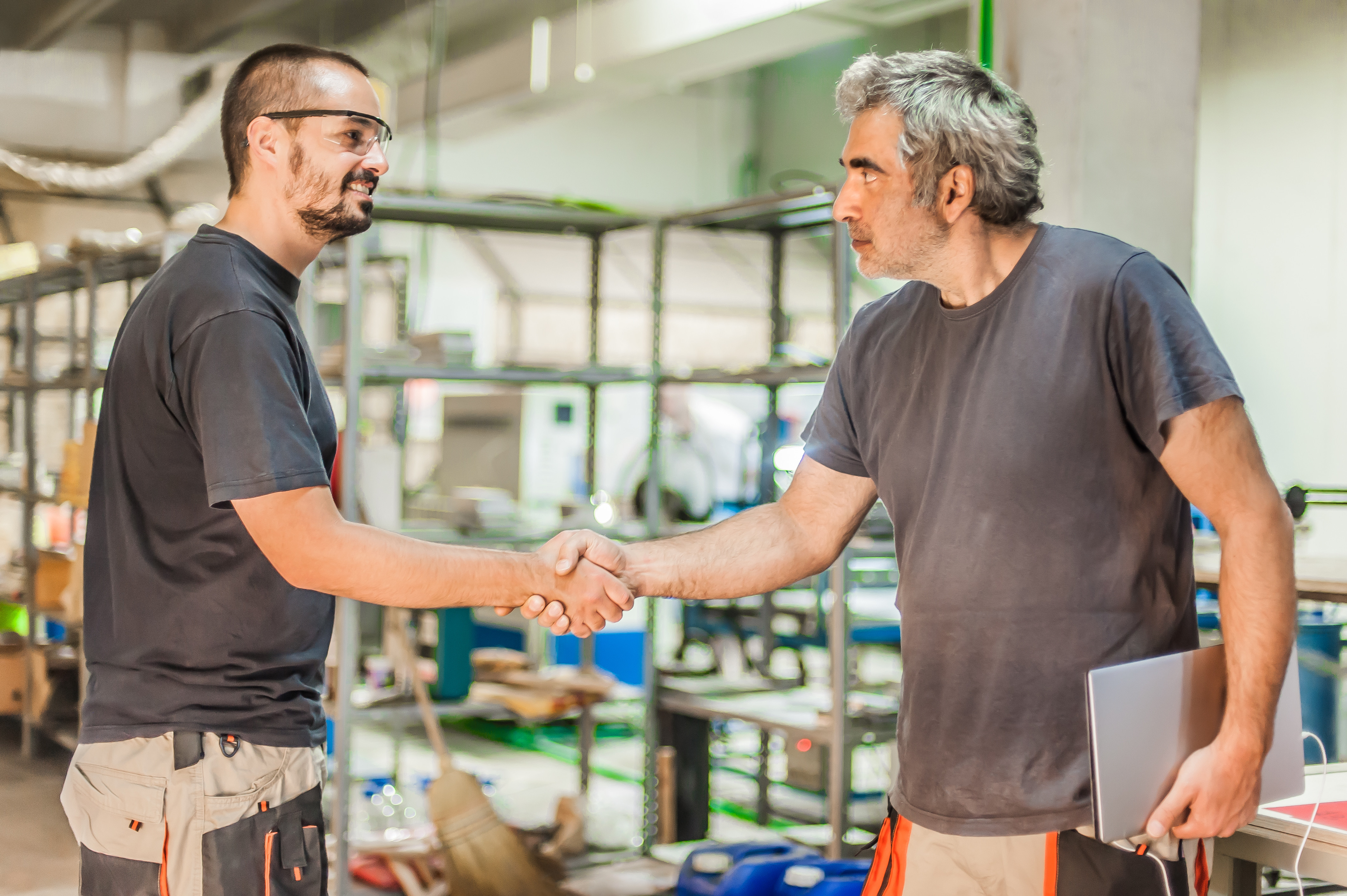 Two workers shaking hands in a manufacturing facility