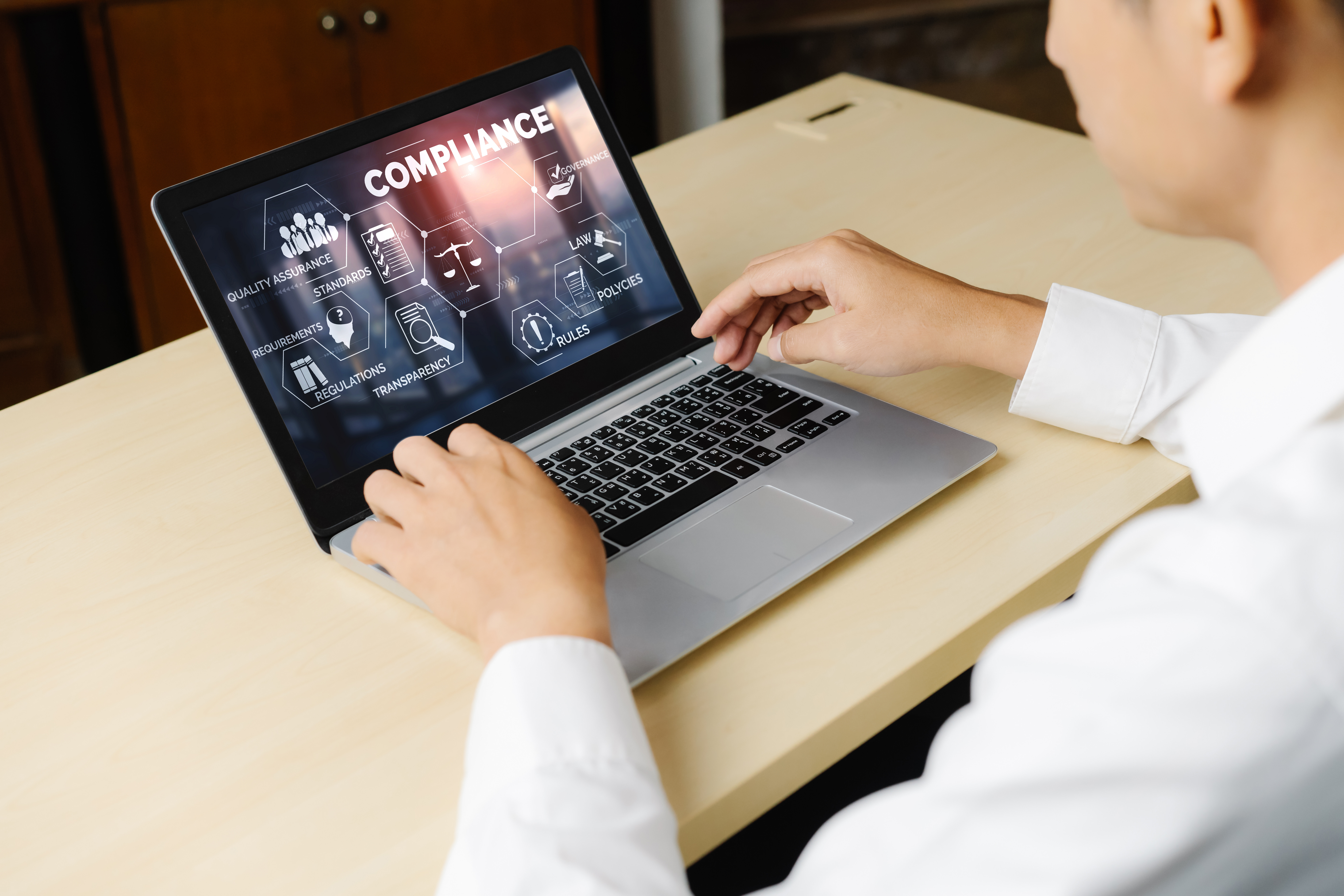 Person viewing a laptop screen with compliance dashboard